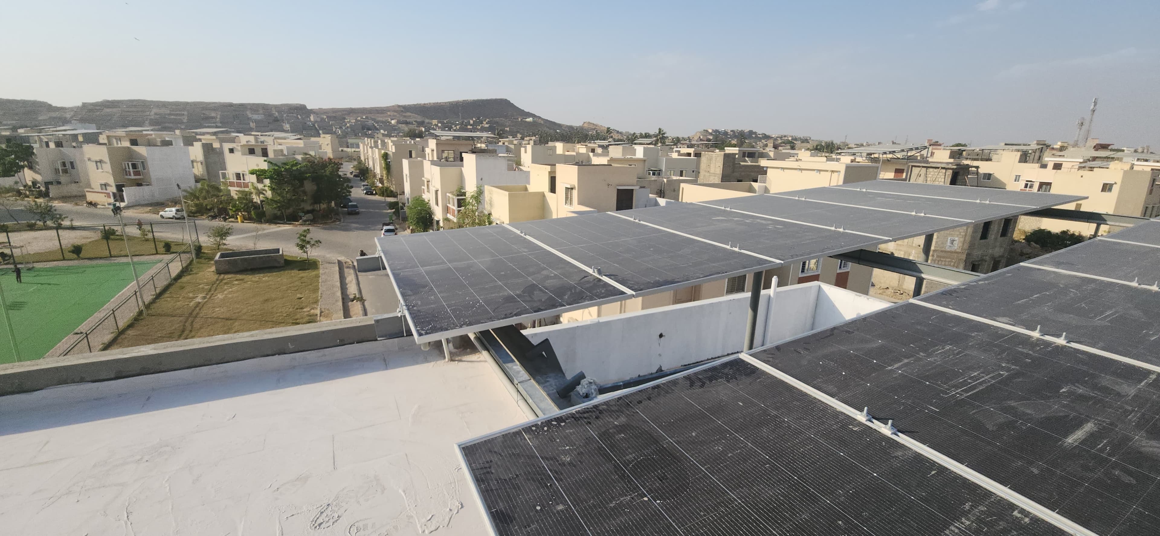 Wide finished rooftop solar installation overlooking a Karachi neighborhood.